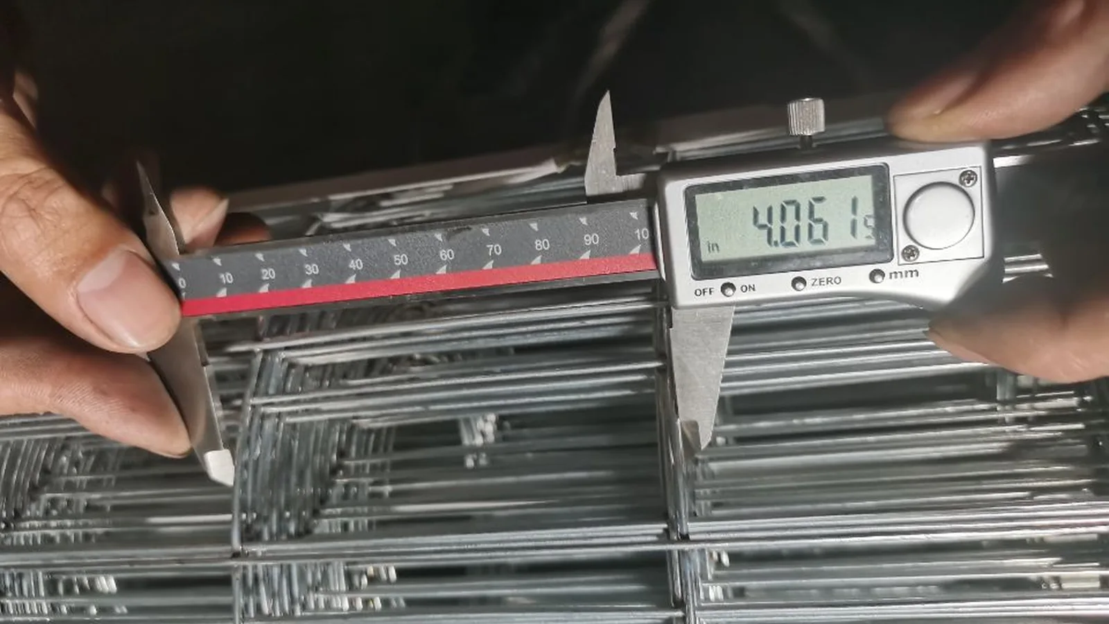 Digital caliper measuring welded wire mesh during inspection at the Leeter factory